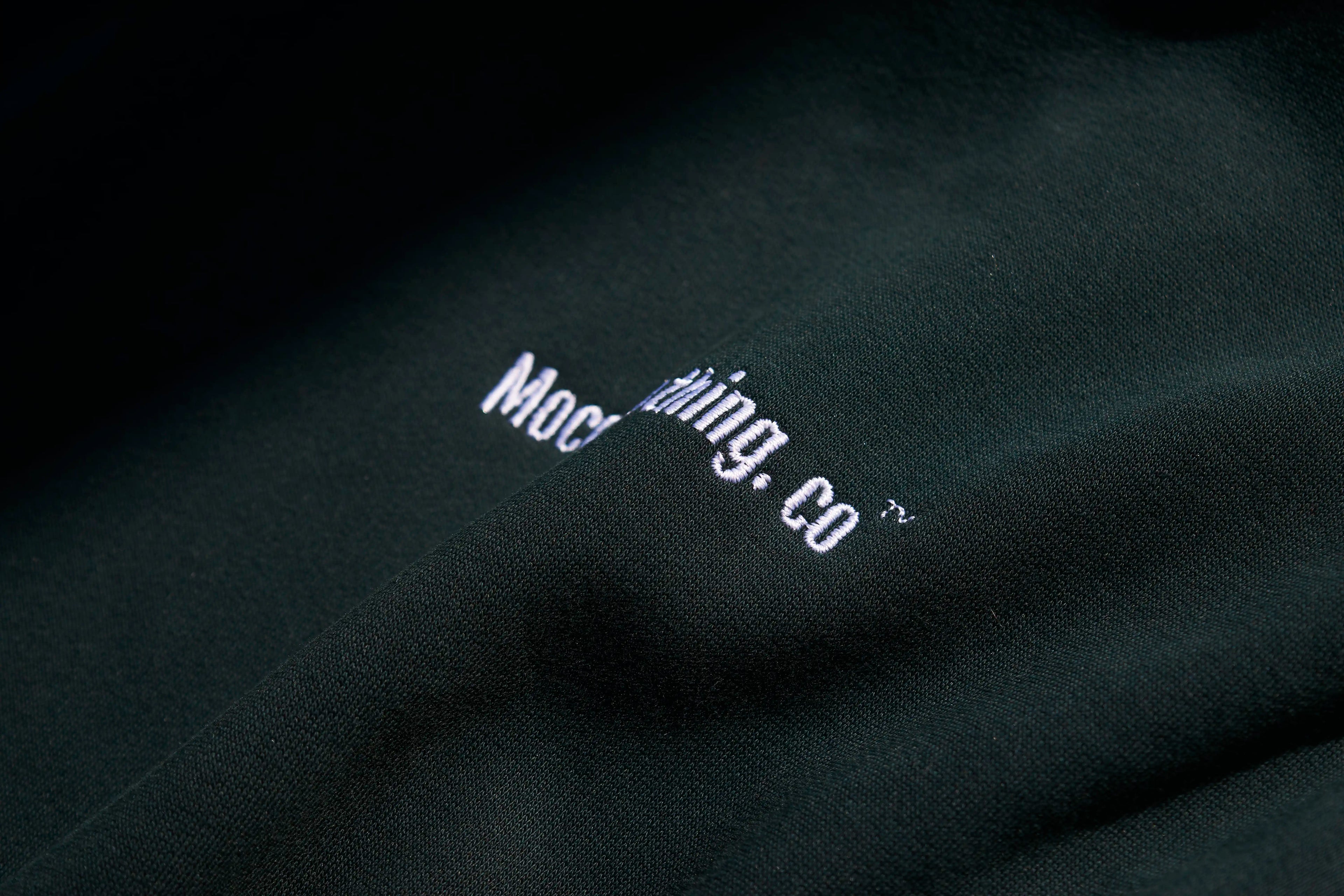 Close-up of a black fabric with white embroidered text on a dark background
